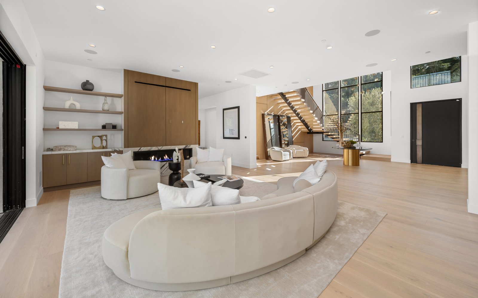 White sofas arranged in a sleek living room beneath a modern glass wall